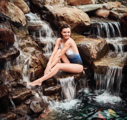 Sitting comfortably on a waterfall, newly engaged model Miranda Kerr dons a blue, white and black swimsuit. Image courtesy of @mirandakerr