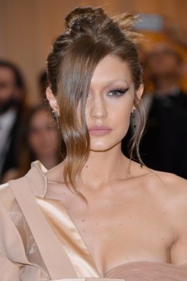 Try a deconstructed top knot for a softer look. Comb hair back loosely into a high ponytail and pull out a partition of hair at the front. Secure ponytail into a messy top knot and use a straightening iron to add a slight kink to the loose hair at the front.