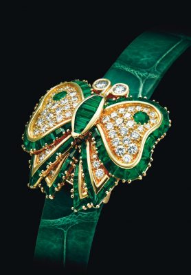 This emerald and diamond watch by Audemars Piguet was sold at Christie’s Auction House. The circular green engine-turned dial is concealed under a butterfly cover that’s smothered in circular-cut diamonds. The piece is further lined by baguette and whistle-cut emeralds and accented by circular-cut emeralds.