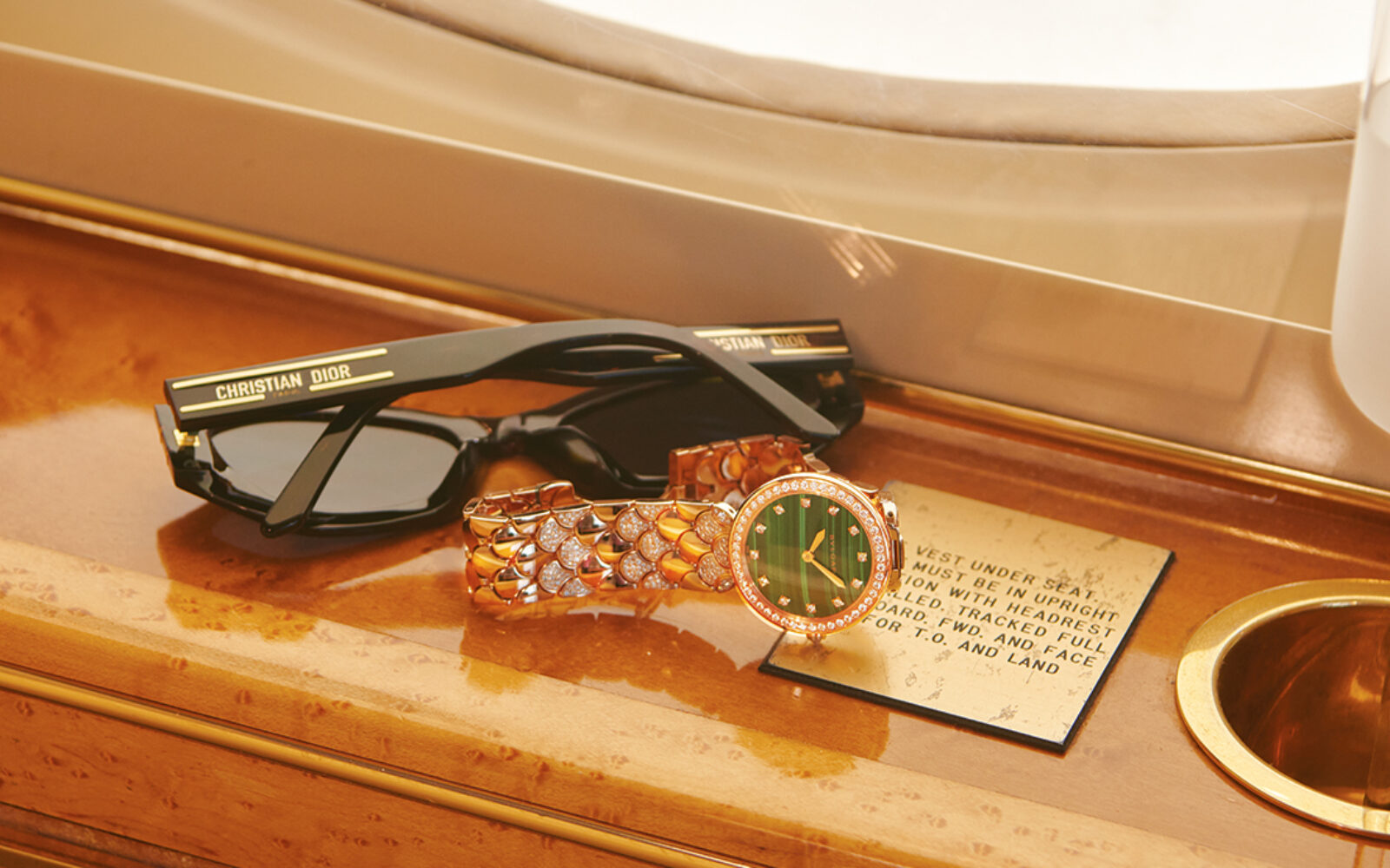 Travel watch; Rolex and Dior sunglasses on the armrest of a private jet