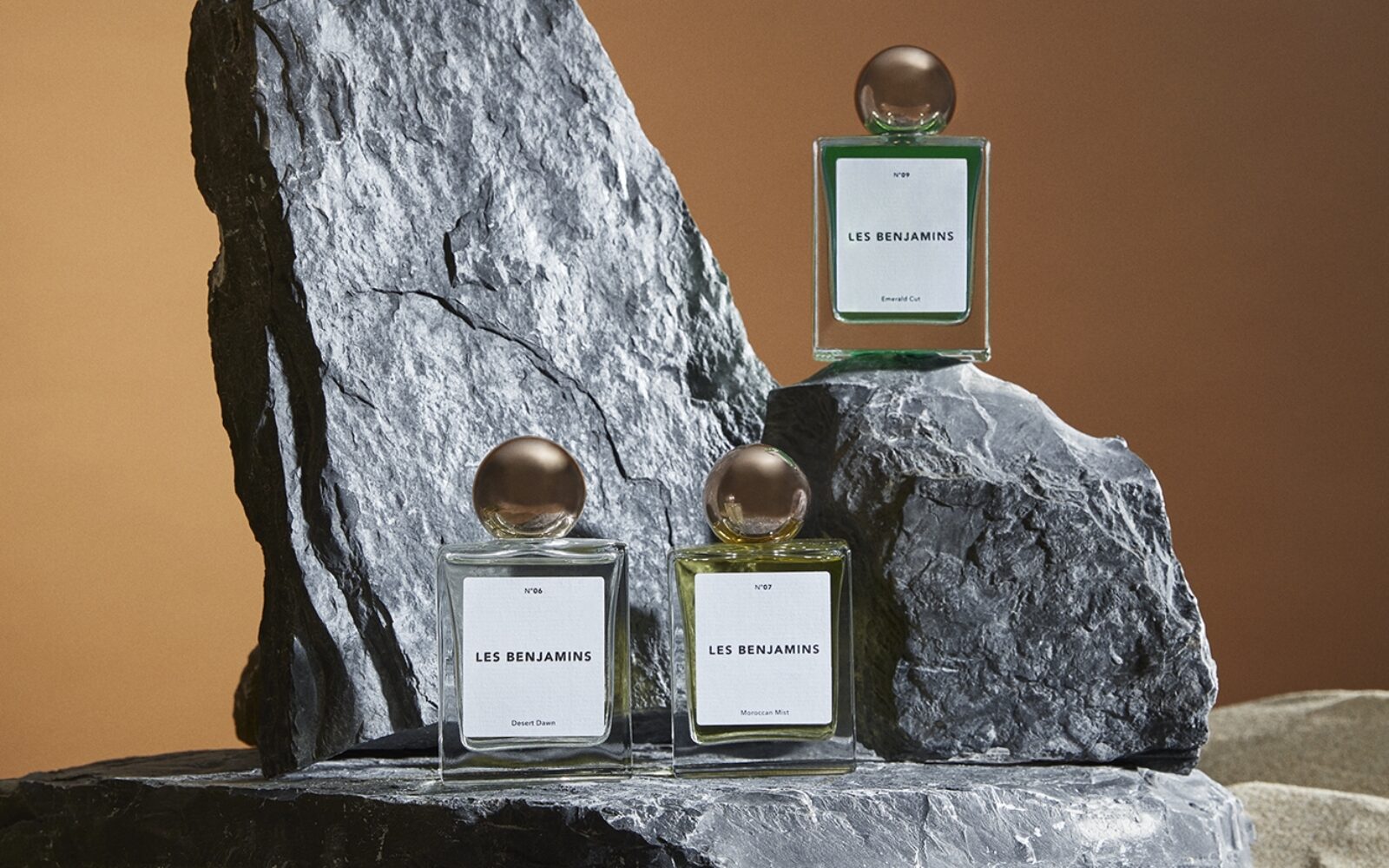 Three bottles of Les Benjamins fragrance Notes of Nostalgia photographed on a rock