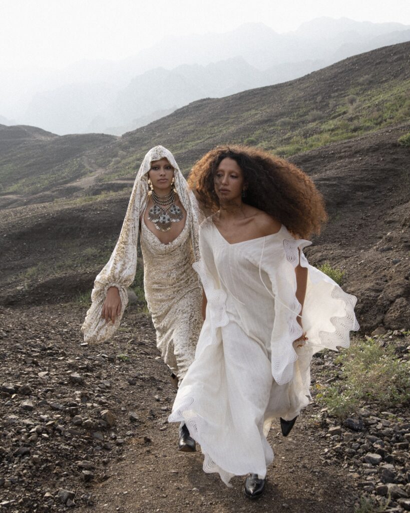 Two women in white dresses walking up a mountain
